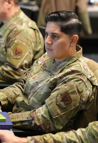 uniformed U.S. Air Force Airmen stand around conference table