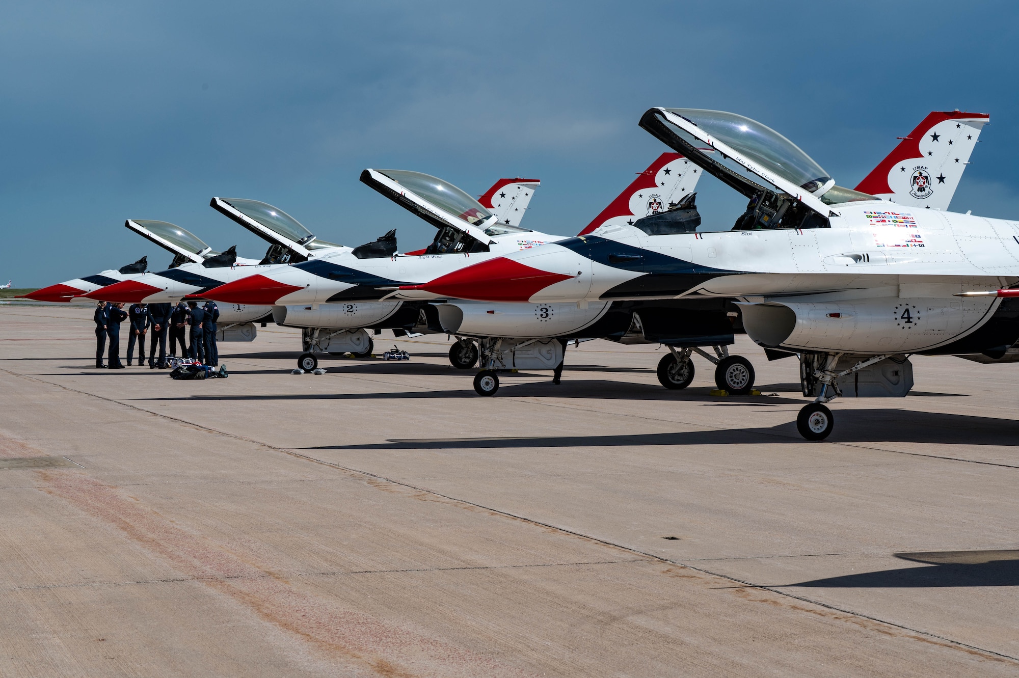 4 Thunderbird F16s parked on the Peterson SFB flightline, with the Thunderbirds team huddled up near jets 1 and 2.