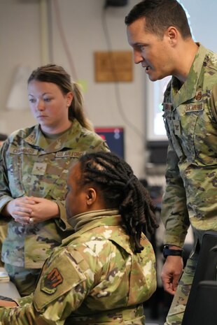 uniformed U.S. Air Force Airmen look at computer screen
