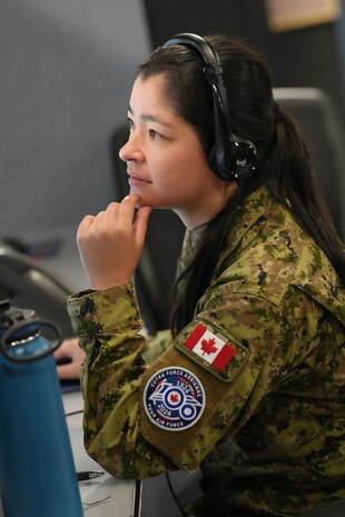 uniformed coalition member wearing a headset working on a computer
