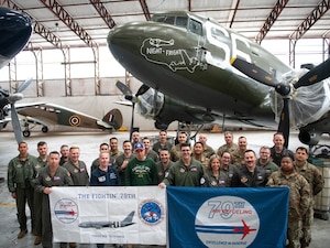 Airmen posing in front of C-47 Night Fright with owner and engineer of restoration project in hangar bay.