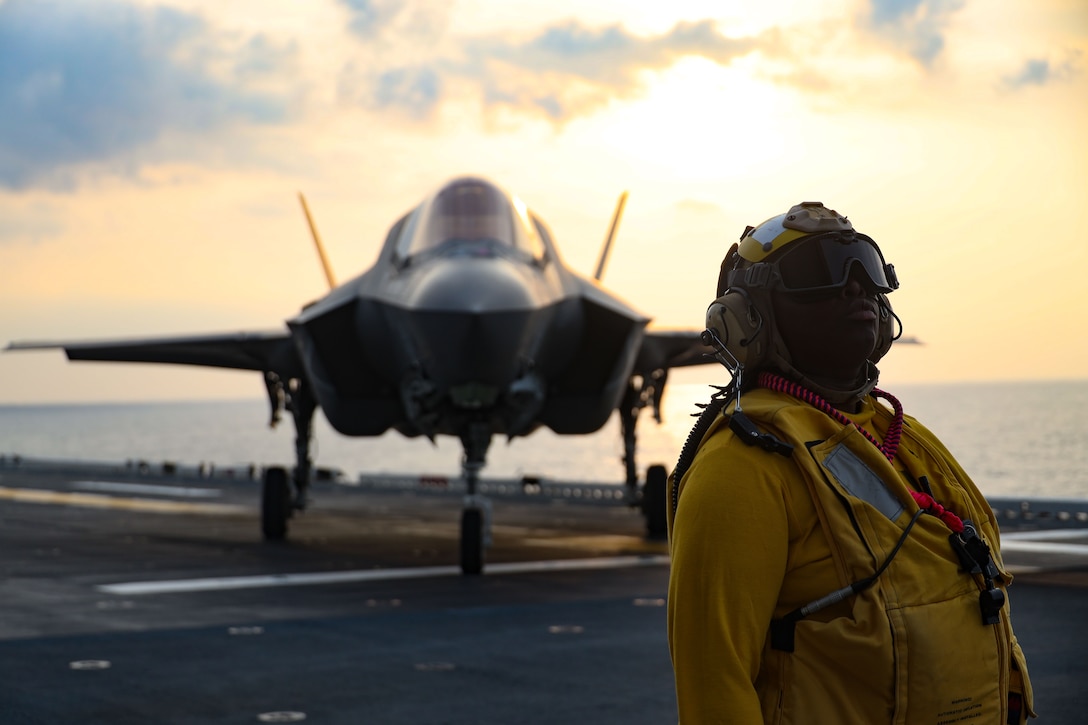 A U.S. Navy Sailor aboard the USS America amphibious assault ship (LHA 6) guides a Marine Corps F-35B lightning II aircraft assigned to Marine Fighter Attack Squadron (VMFA) 242, 31st Marine Expeditionary Unit, around the flight deck during night flight operations in the Philippine Sea, May 31, 2025. Marine F-35Bs bring a 5th generation multi-discipline strike capability to support combined-joint all domain operations in key maritime terrain. The 31st MEU is operating aboard ships of the USS America Amphibious Ready Group in the 7th Fleet area of operations, the U.S. Navy’s largest forward-deployed numbered fleet, and routinely interacts and operates with allies and partners in preserving a free and open Indo-Pacific region. (U.S. Marine Corps photo by Sgt. Peter Rawlins)