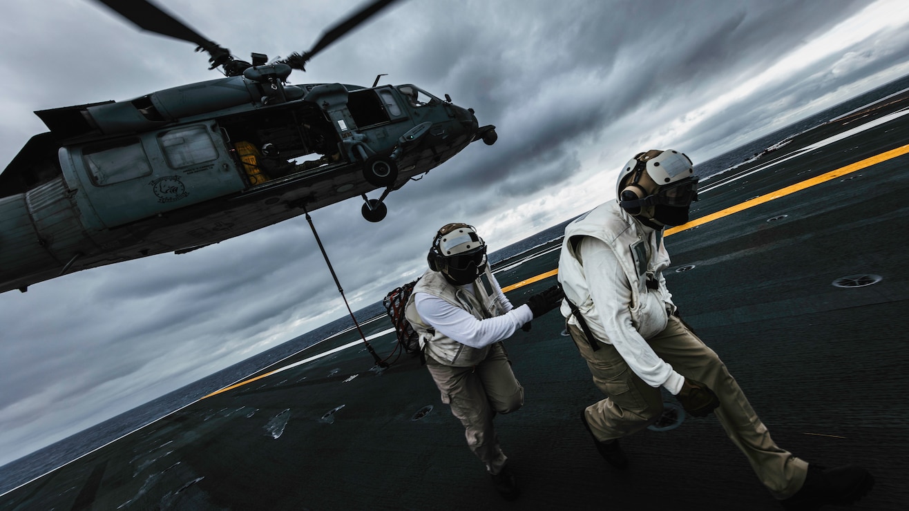 Chief Logistics Specialist Jonathan Cruz, right, from Olongapo, Philippines, and Chief Logistics Specialist Antonio Evans, from Los Angeles, both assigned to supply department’s aviation supply division, participate in vertical replenishment training on the flight deck of Nimitz-class aircraft carrier USS George Washington (CVN 73) while underway in the Philippine Sea, May 28, 2025.