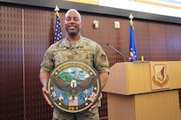 U.S. Airman stands holding a Bamboo Eagle Emblem