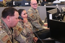 uniformed U.S. Airmen work on computers