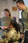 uniformed U.S. Air Force Airmen look at computer screen