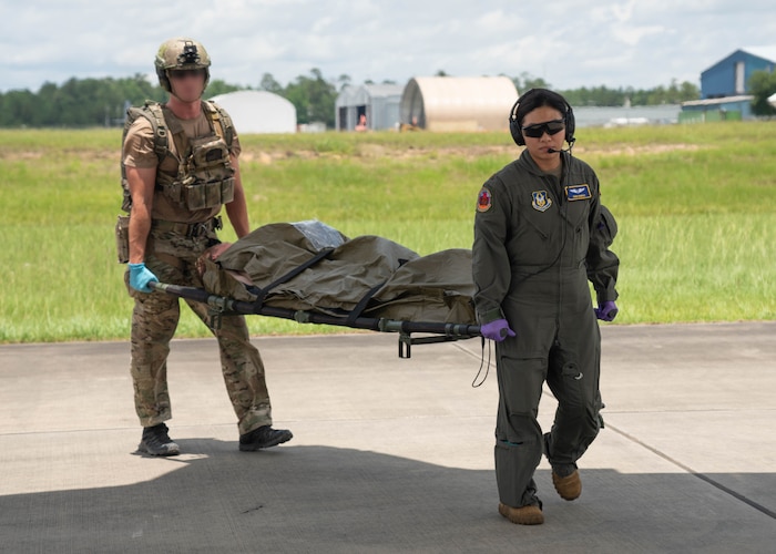 military members carrying litter with patient.