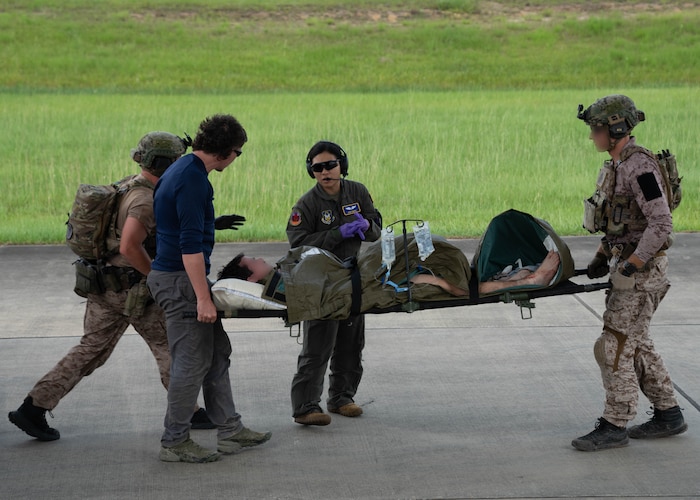 military members carrying patient litters during a joint training exercise.