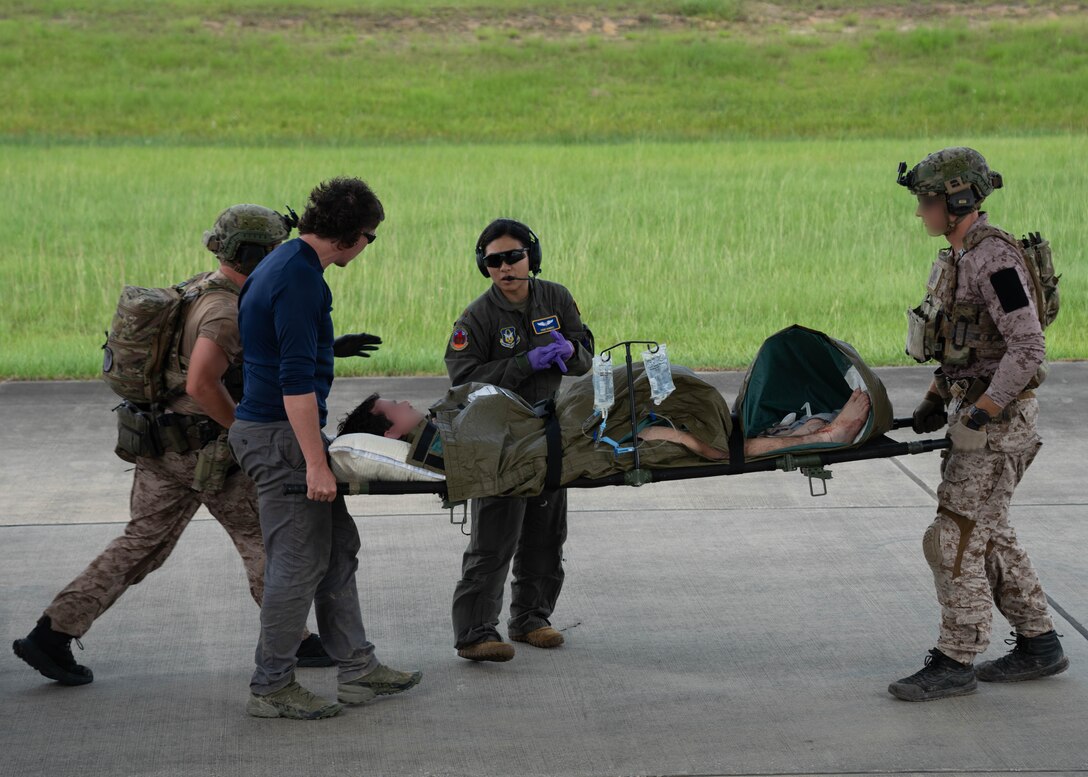 military members carrying patient litters during a joint training exercise.