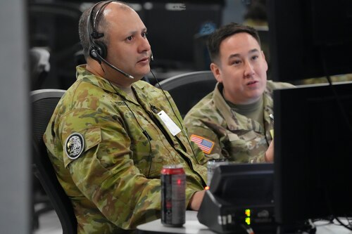 uniformed coalition and US military members work on computers