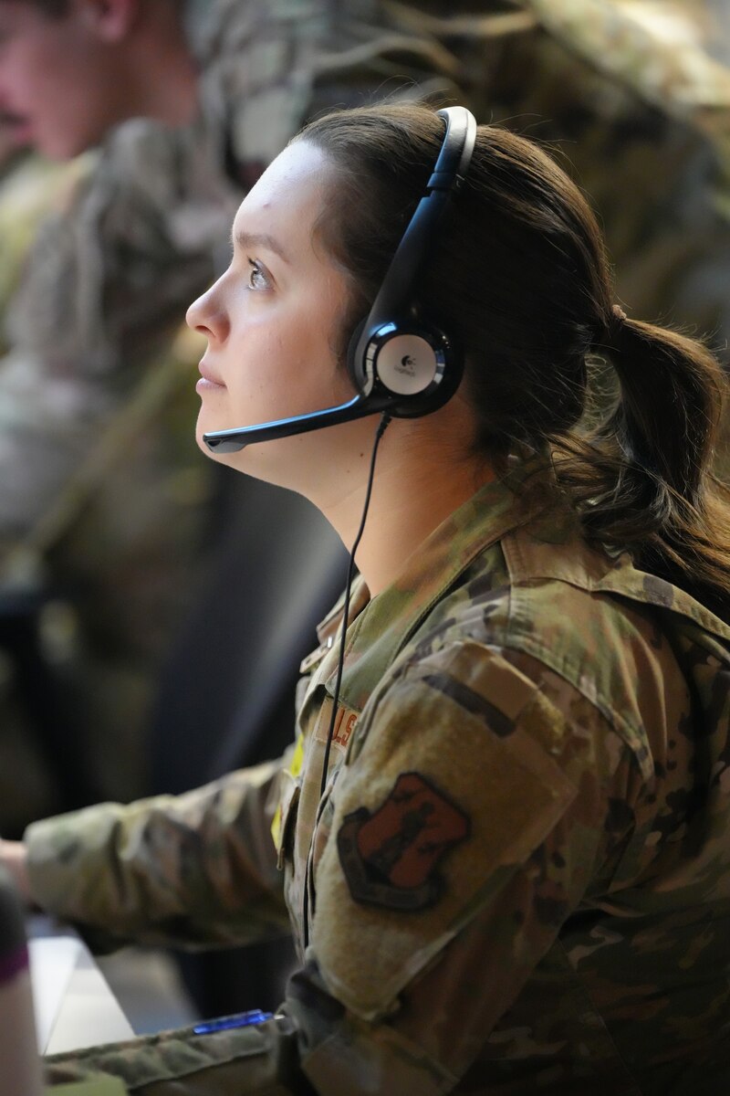 uniformed US Air Force Airman wearing a headset works on a computer