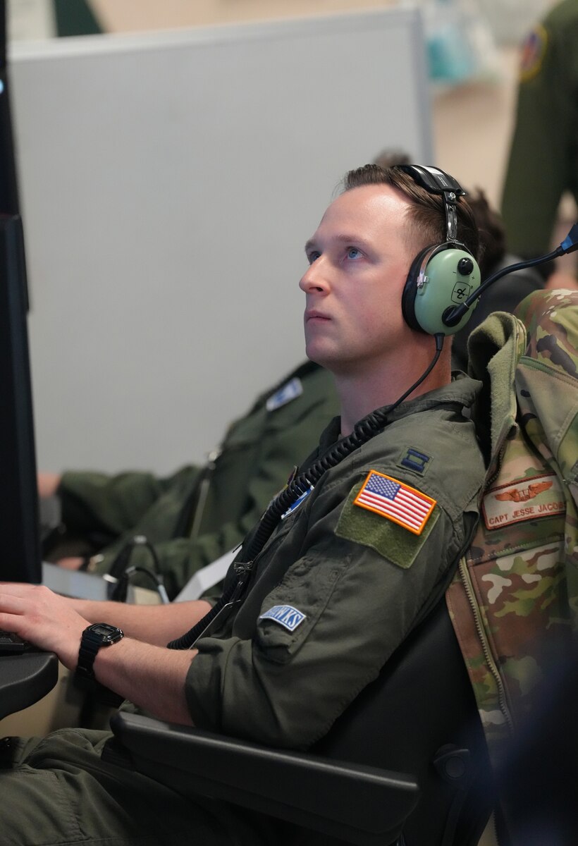 Uniformed U.S. Air Force pilot wearing a headset flys aircraft from simulator
