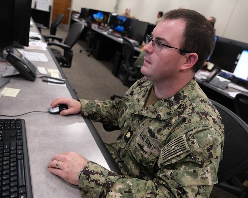 uniformed U.S. Navy Sailor works at a computer
