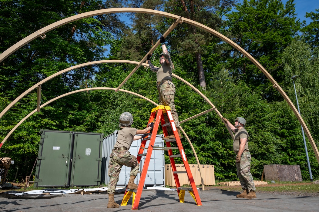 U.S. Air Force Senior Airman Coleen Tabdim, 786th Force Support Squadron readiness journeyman, Tech. Sgt. Rebecca Joplin, 786th FSS food services production manager, and Tech. Sgt. Bradlee Brown, noncommissioned officer in charge of mortuary affairs, construct an Alaska Small Shelter System during Operation Steel at the 435th Construction and Training Squadron Compound near Ramstein Air Base, Germany, May 29, 2025.