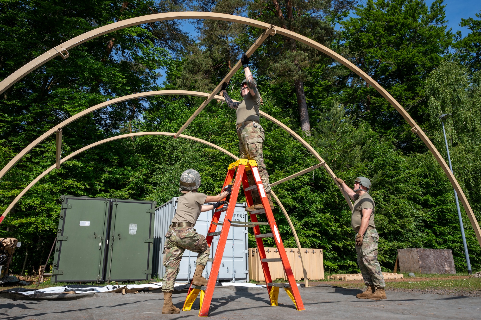 U.S. Air Force Senior Airman Coleen Tabdim, 786th Force Support Squadron readiness journeyman, Tech. Sgt. Rebecca Joplin, 786th FSS food services production manager, and Tech. Sgt. Bradlee Brown, noncommissioned officer in charge of mortuary affairs, construct an Alaska Small Shelter System during Operation Steel at the 435th Construction and Training Squadron Compound near Ramstein Air Base, Germany, May 29, 2025.