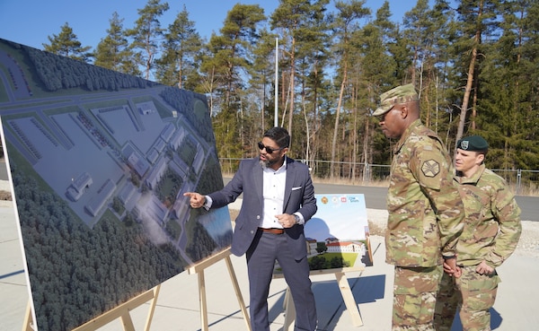 Man points to poster in front of two other men