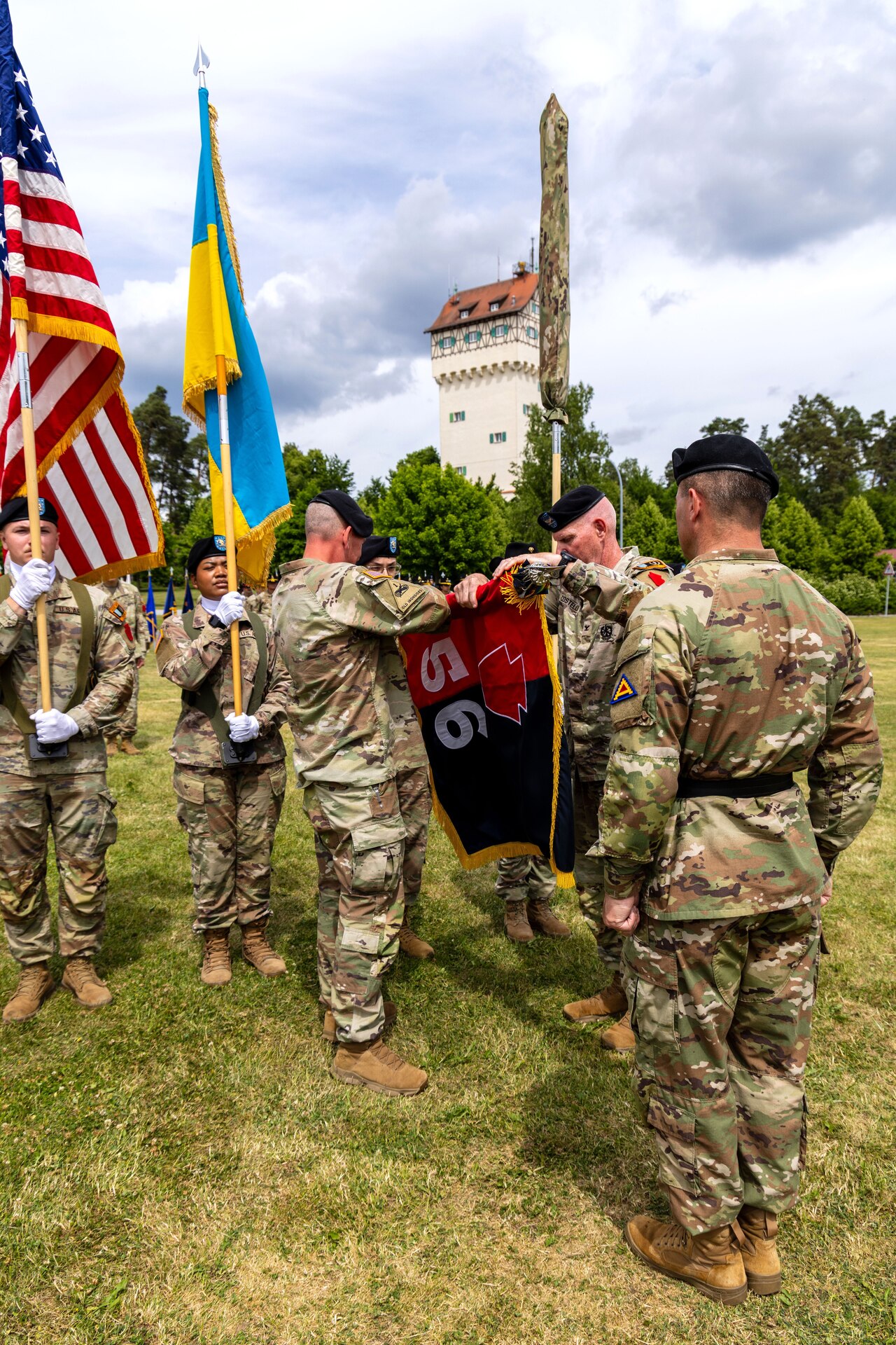 U.S. Army Col. Christopher Costello, commander of the 56th Stryker Brigade Combat Team, Pennsylvania National Guard, and Command Sgt. Maj. James Short, command sergeant major of the 56th SBCT, case the brigade colors while U.S. Army Brig. Gen. Steven Carpenter, commanding general of the 7th Army Training Commander, looks on at the Joint Multinational Training Group-Ukraine transfer of authority ceremony at Tower Barracks, Grafenwoehr, Germany, June 1, 2025. The ceremony commemorated the transfer of the JMTG-U mission from the 56th SBCT to the 278th Armored Cavalry Regiment, Tennessee National Guard. (U.S. Army National Guard photo by Capt. Leanne Demboski)