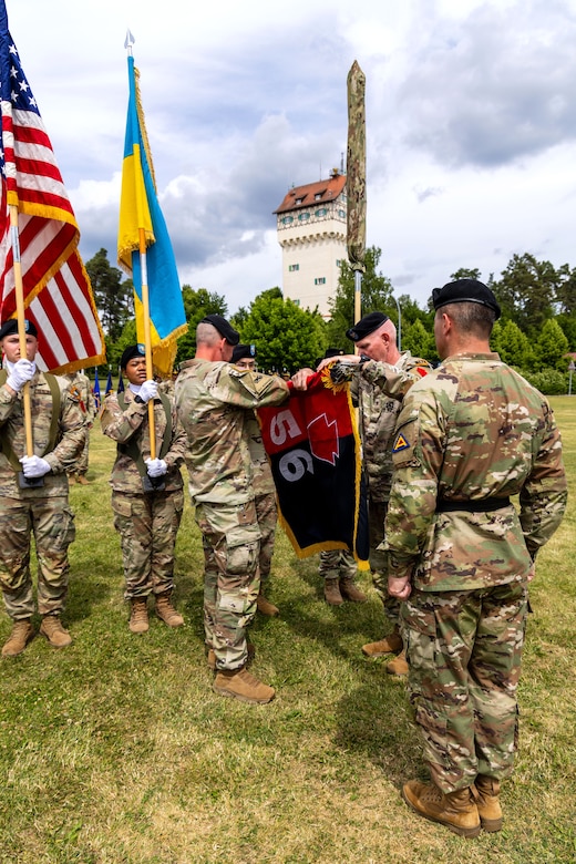 U.S. Army Col. Christopher Costello, commander of the 56th Stryker Brigade Combat Team, Pennsylvania National Guard, and Command Sgt. Maj. James Short, command sergeant major of the 56th SBCT, case the brigade colors while U.S. Army Brig. Gen. Steven Carpenter, commanding general of the 7th Army Training Commander, looks on at the Joint Multinational Training Group-Ukraine transfer of authority ceremony at Tower Barracks, Grafenwoehr, Germany, June 1, 2025. The ceremony commemorated the transfer of the JMTG-U mission from the 56th SBCT to the 278th Armored Cavalry Regiment, Tennessee National Guard. (U.S. Army National Guard photo by Capt. Leanne Demboski)
