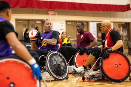 U.S. Army Capt. Carlos Rivera, left, prepares to throw the ball before being defended by Master Sgt. Earlie Brown, center, and Sgt. 1st Class David Hoang, right, during wheelchair rugby practice at the 2025 Army Trials, Fort Bliss, Texas, April 4, 2025.
