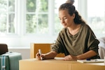 Woman writes at a desk.