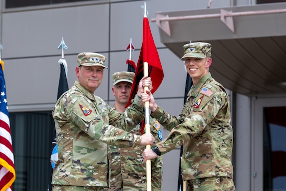 two military men in uniform stand together holding a guidon
