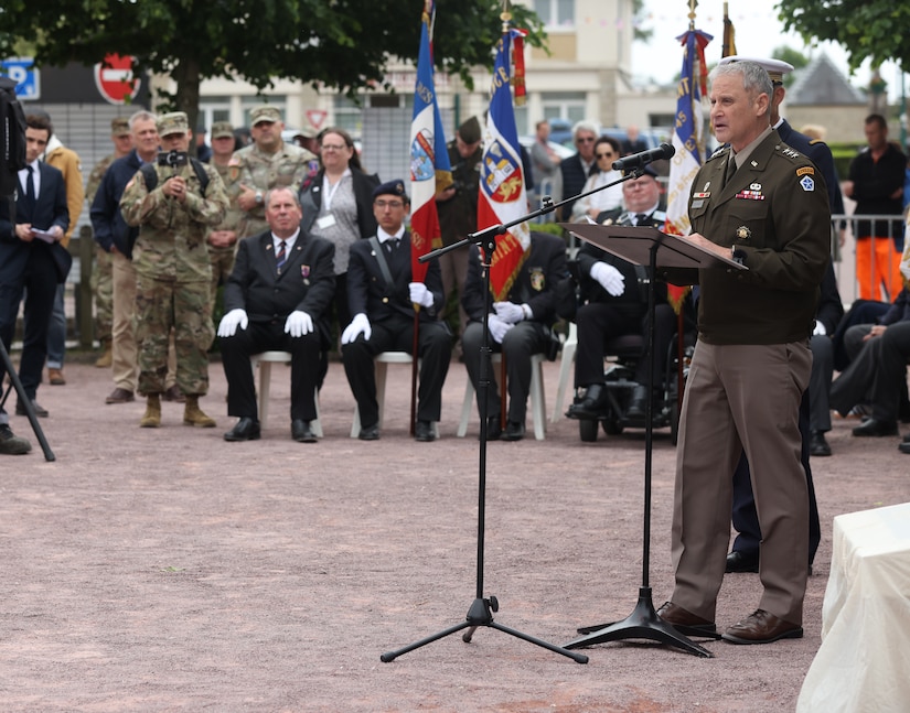 U.S. Army Lt. Gen. Charles Costanza, commanding general of V Corps, speaks beneath a statue of Gen. Dwight D. Eisenhower in Sainte-Mère-Église, France, June 2, 2025. The statue, unveiled in 2024, honors Eisenhower’s legacy and symbolizes Allied unity. (U.S. Army photo by Sgt. Tyler Brock)