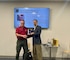 One man giving another man an award while shaking hands.