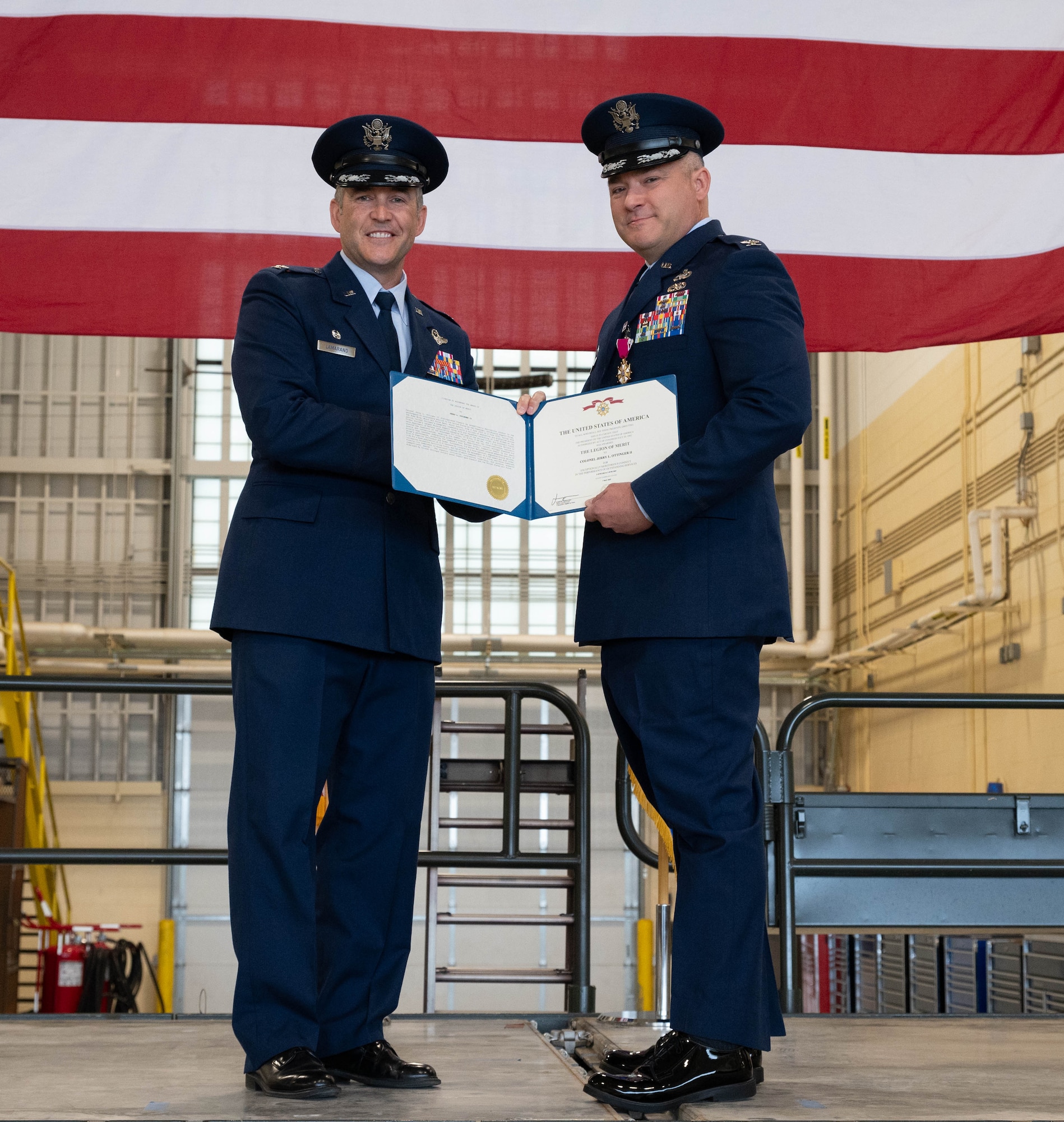 U.S. Air Force Col. Jesse Lamarand, 5th Bomb Wing Commander (left), and U.S. Air Force Col. Jerry Ottinger, 5th Mission Support Group commander (right), pose for a picture with a Legion of Merit award at Minot Air Force Base, North Dakota, June 2, 2025. The Legion of Merit is an award that is earned through exceptionally meritorious conduct in the performance of outstanding services and achievements. (U.S. Air Force photo by Airman 1st Class Wesley Davies)