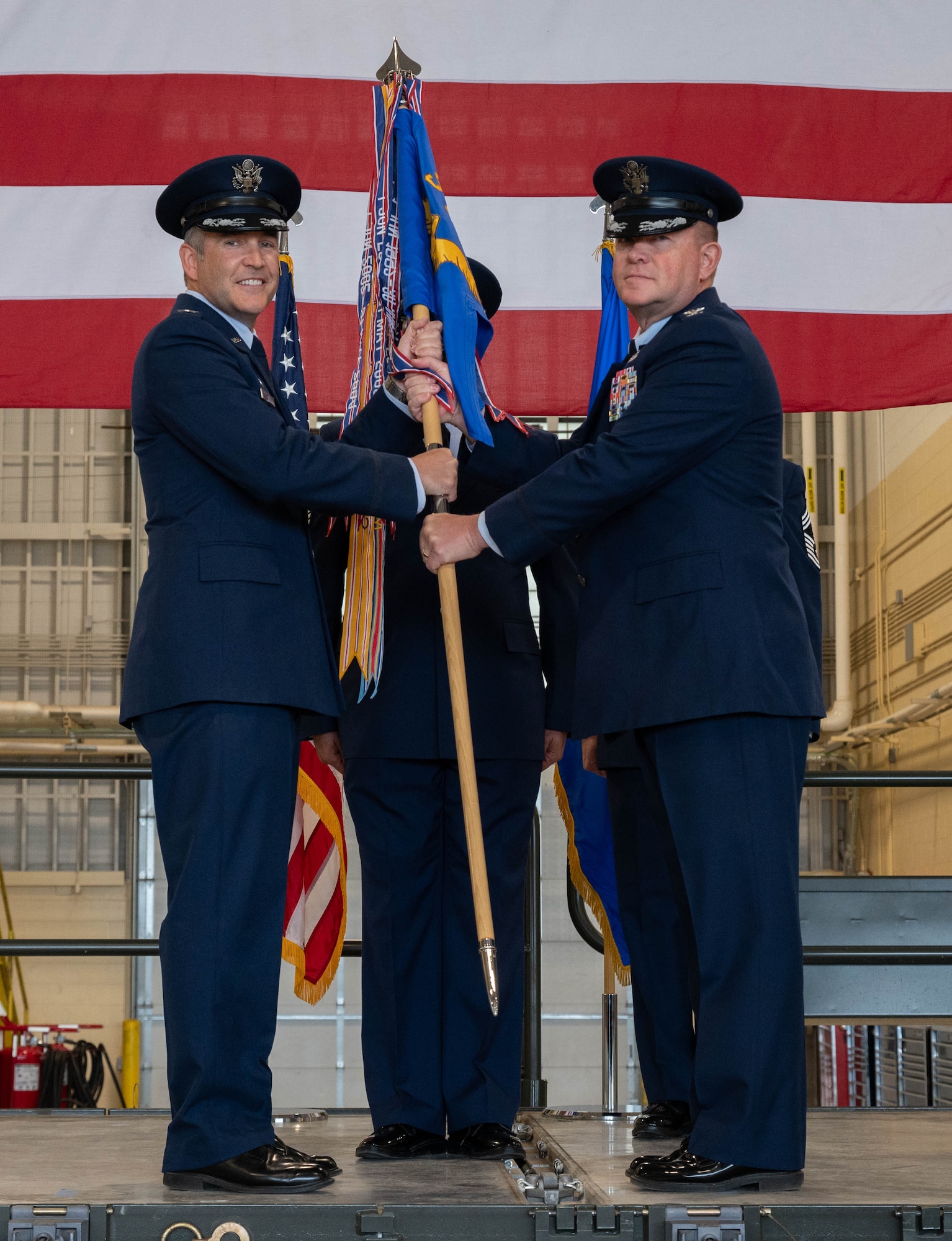 U.S. Air Force Col. Richard Zeigler, incoming 5th Mission Support Group (5MSG) commander (right), accepts the 5MSG guidon from U.S. Air Force Col. Jesse Lamarand, 5th Bomb Wing commander (left), during a change of command ceremony at Minot Air Force Base, North Dakota, June 2, 2025. Lamarand passed the guidon to Zeigler during the ceremony, symbolically passing command of the 5MSG. (U.S. Air Force photo by Airman 1st Class Wesley Davies)