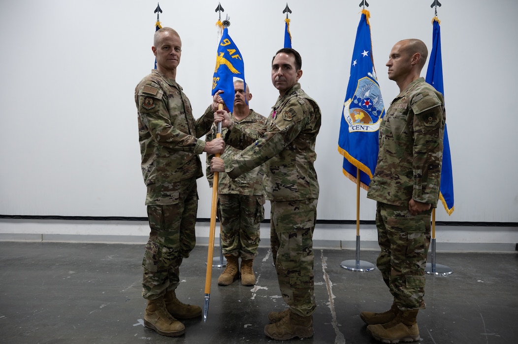 U.S. Air Force Col. Matthew Borawski, outgoing 1st Expeditionary Theater Support Group commander, right, hands the guidon to U.S. Air Force Lt. Gen. Derek France, left, Ninth Air Force (Air Forces Central) commander, during the 1st ETSG change of command ceremony within the U.S. Central Command area of responsibility, May 30, 2025. One of the 1st ETSG’s main objectives is campaigning and setting the theater for Agile Combat Employment. (U.S. Air Force photo by Senior Airman Dieondiere Jefferies)