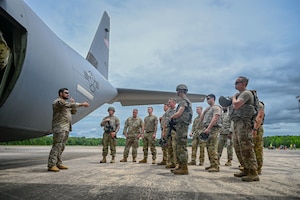 Airmen gather in front of a C130J Super Hercules aircraft.