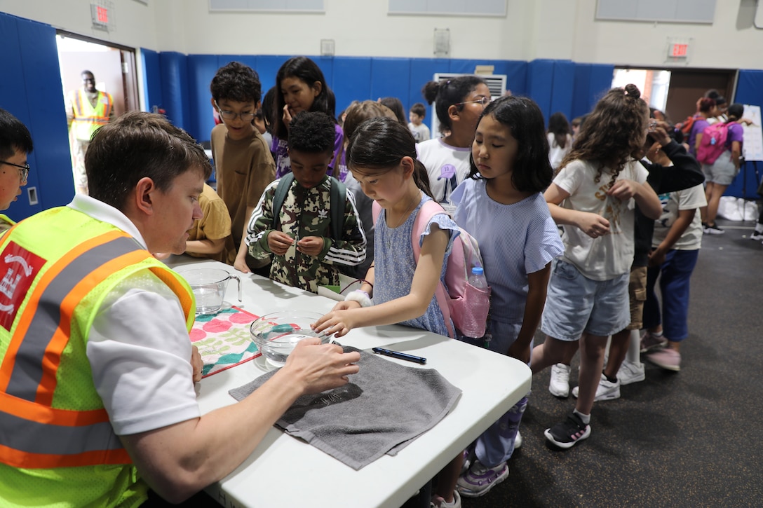 Daniel Carlson, Fire Protection Engineer, U.S. Army Corps of Engineers – Far East District, demonstrates the concept of water surface tension to students at a Science, Technology, Engineering, Arts and Mathematics (STEAM) event hosted by USACE at West Elementary School on Camp Humphreys, South Korea, on May 22, 2025. Through interactive experiments, Carlson inspires curiosity and a deeper understanding of scientific principles. (U.S. Army photo by Yohan An)