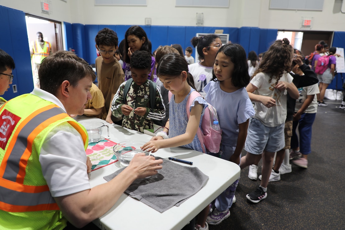 Daniel Carlson, Fire Protection Engineer, U.S. Army Corps of Engineers – Far East District, demonstrates the concept of water surface tension to students at a Science, Technology, Engineering, Arts and Mathematics (STEAM) event hosted by USACE at West Elementary School on Camp Humphreys, South Korea, on May 22, 2025. Through interactive experiments, Carlson inspires curiosity and a deeper understanding of scientific principles. (U.S. Army photo by Yohan An)