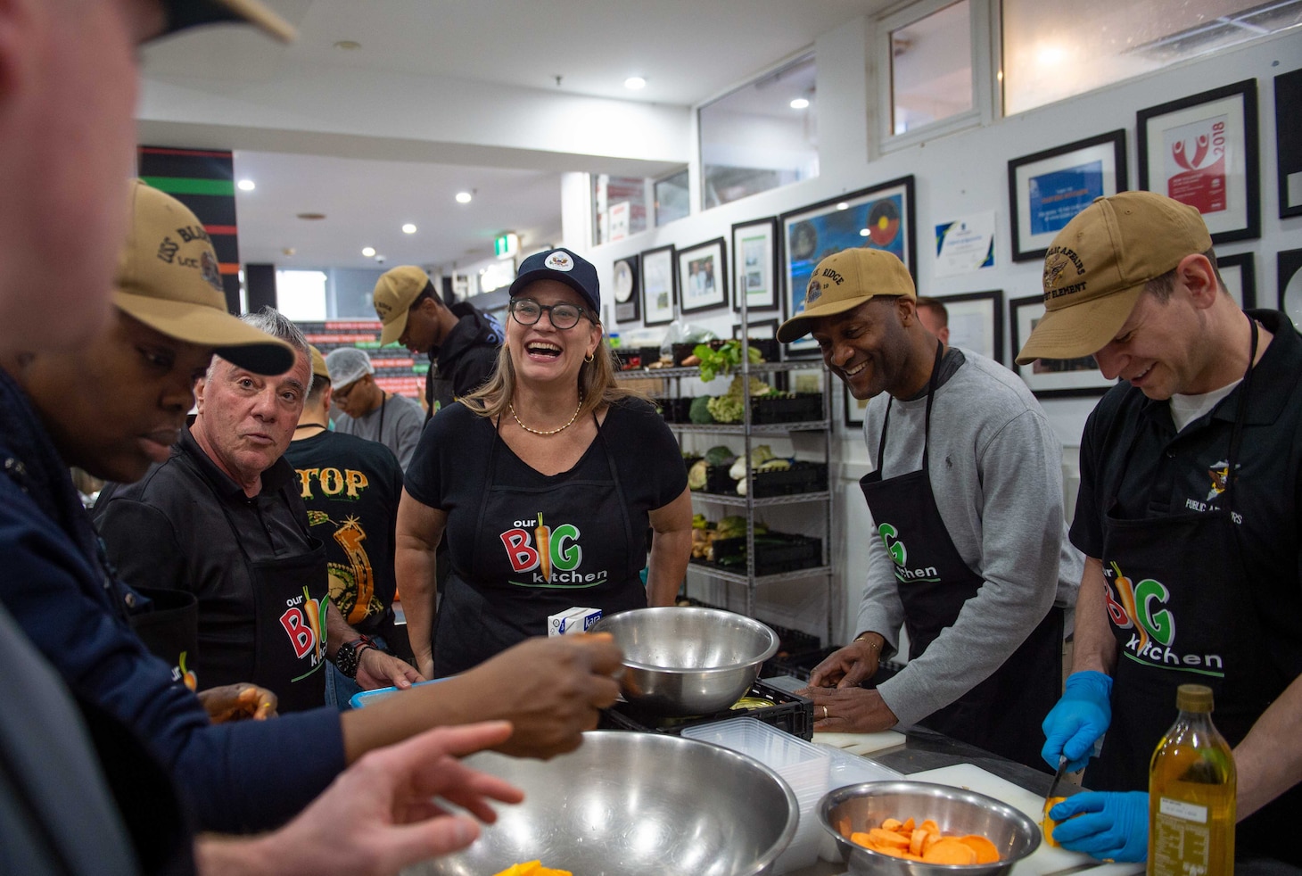 SYDNEY (May 28, 2025) – U.S. Chargé d’Affaires Erika Olson and Sailors assigned to U.S. 7th Fleet and 7th Fleet flagship USS Blue Ridge (LCC 19) prepare food while volunteering with the nonprofit organization Our Big Kitchen during a scheduled port visit in Sydney, May 28, 2025. The Blue Ridge and embarked 7th Fleet staff conduct regular Indo-Pacific patrols to deter aggression, strengthen alliances and partnerships, and advance future warfighting capabilities. (U.S. Navy photo taken by Mass Communication Specialist Seaman Alajia Williams)