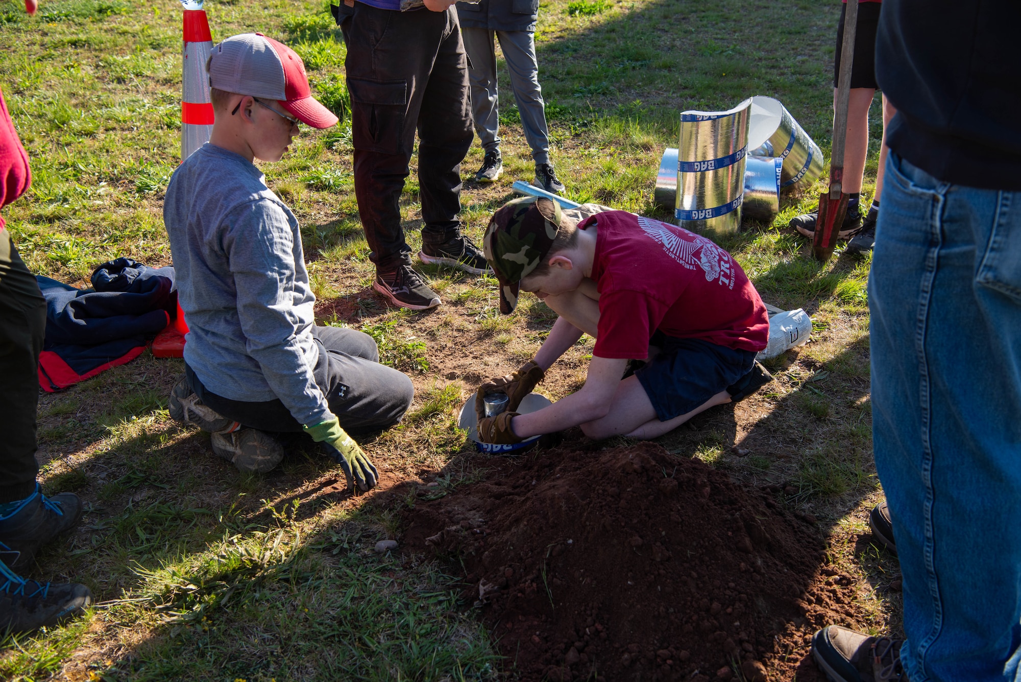 Boy Scouts of America members place a basket anchor sleeve to firmly secure a disc golf basket pole.