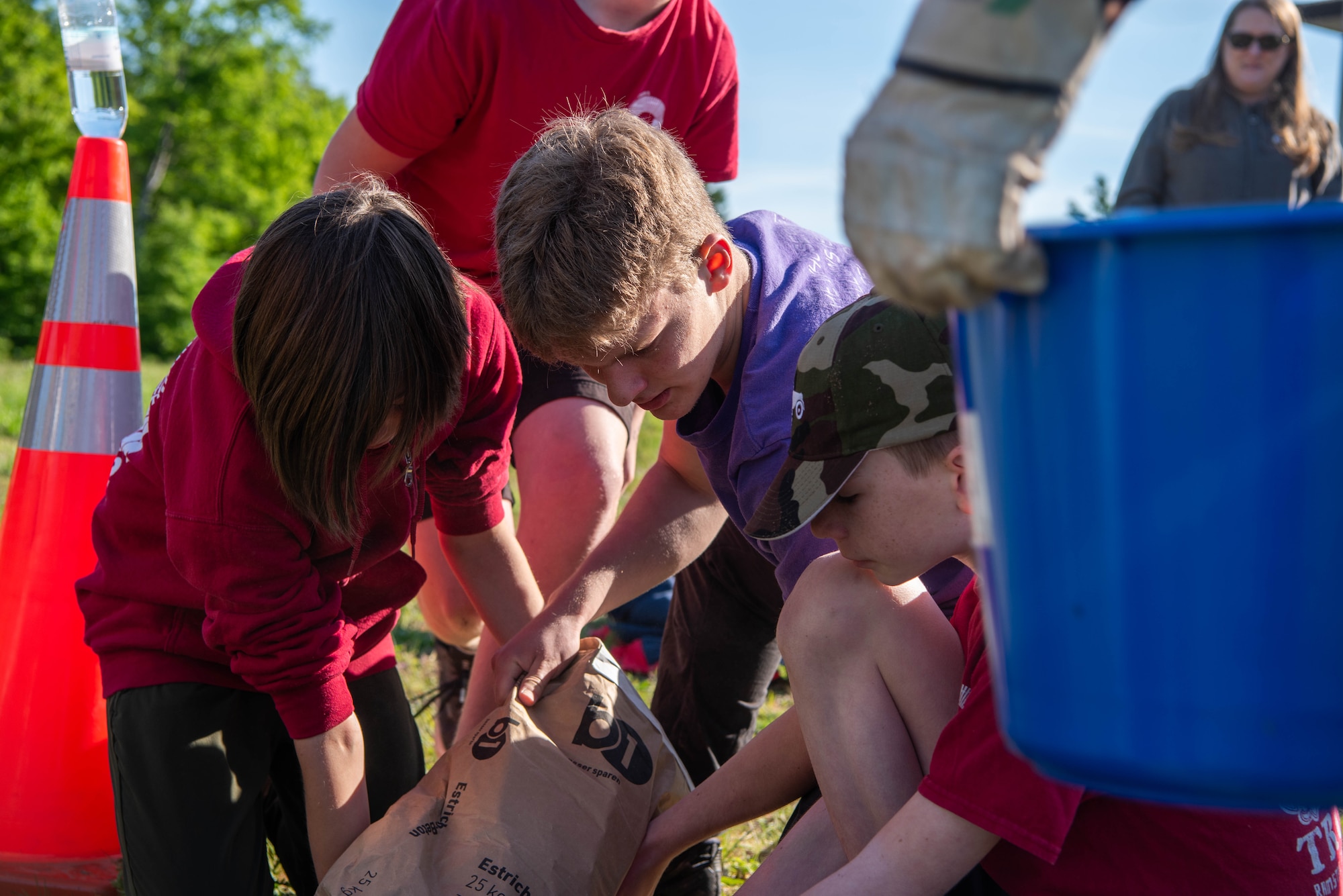 Boy Scouts of America members pour concrete while constructing a disc golf course.