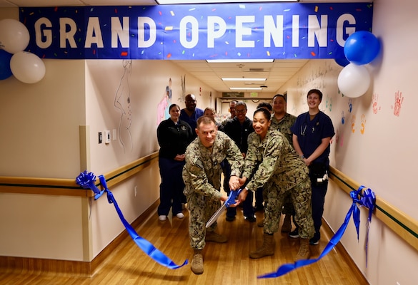 Capt. Daniel Clark (left), commanding officer of Naval Hospital Twentynine Palms, and Cmdr. Christine Higgins (right), Maternal-Infant Nursing Department head and staff certified nurse midwife, cut the ribbon during a ceremony on May 29 marking the relocation and revitalization of the hospital’s Multi-Service Ward. The upgraded space, which houses the Maternal Infant Nursing Department (MIND), enhances inpatient care for military families aboard the Marine Corps Air Ground Combat Center (U.S. Navy photo by Christopher C. Jones, NHTP/NMRTC Twentynine Palms public affairs officer).