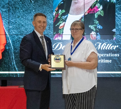 Debbie Miller receives her Hall of Fame award from DLA Land and Maritime Acting Commander Kenneth Watson