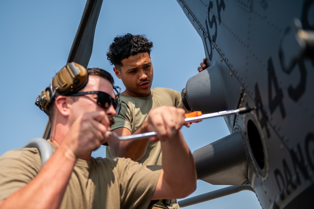 Men turn bolts on helicopter.