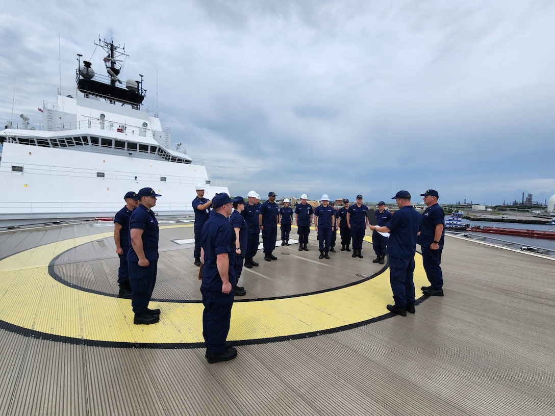 Capt. Keith Ropella reads his orders to assume command of the USCGC Storis during quarters on the cutter’s forward flightdeck.