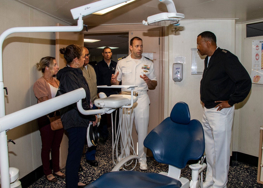 Admiral Alvin Holsey stands on the right while a Navy officer gives a tour of a dental patient room