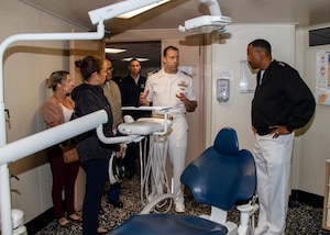 Admiral Alvin Holsey stands on the right while a Navy officer gives a tour of a dental patient room