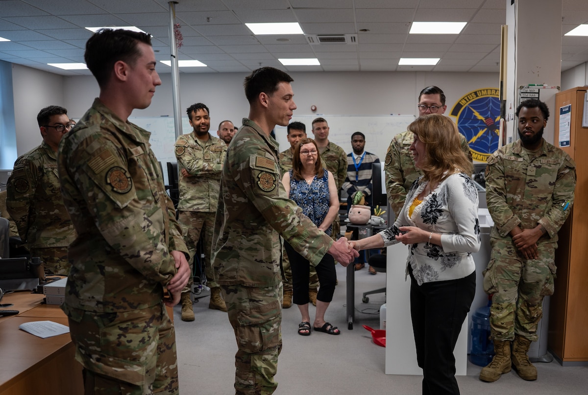 Two service members are given a coin by a member of the Department of the Air Force
