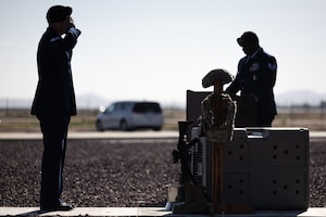 Staff Sgt. Brandon Terrell calls fallen heroes by name, while Staff Sgt. Jacob Yarbrough salutes in front of a display that honors all defenders, including canines, who made the ultimate sacrifice, during Police Week closing ceremony May 16.