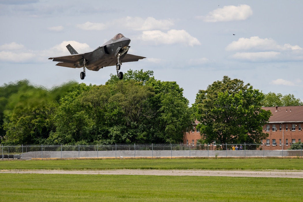 An F-35 comes in for a landing over trees and and runway