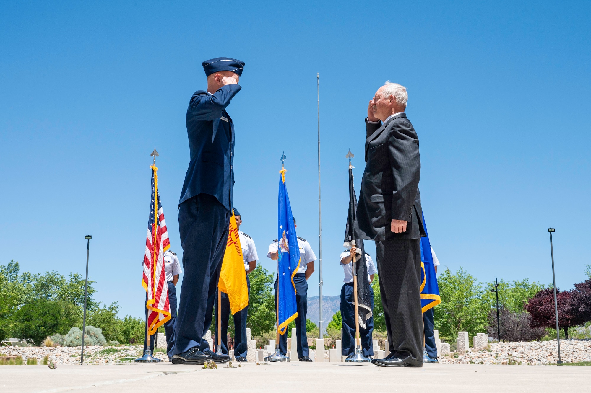 Airman solutes his family member at his swearing in ceremony in front of flags