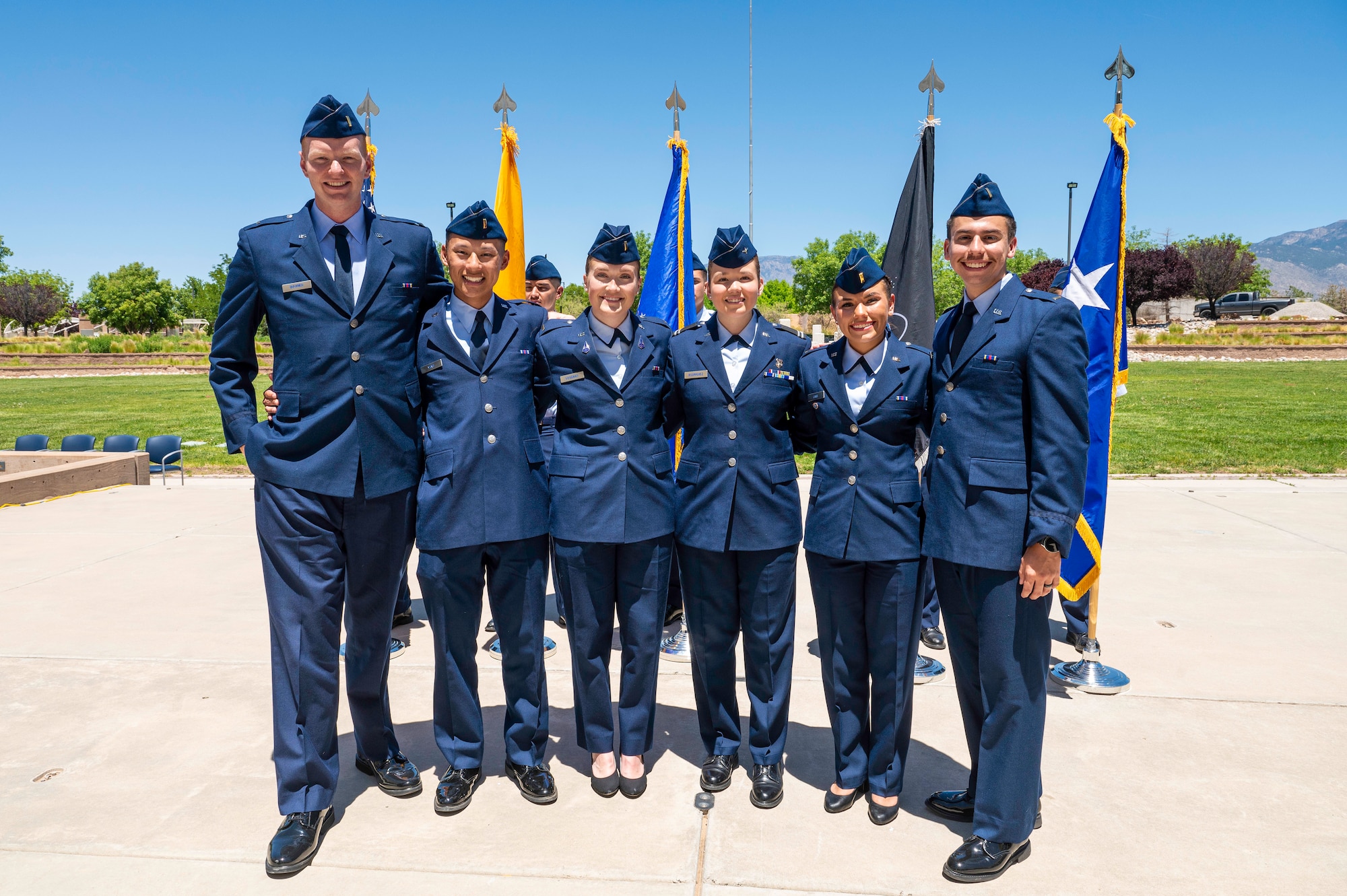 6 uniformed air force members pose for a group photo in front of flags