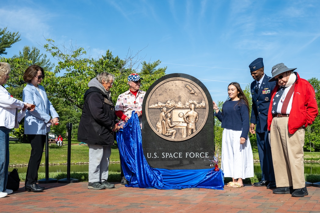 A group of people stand around a stone sculpture signifying the U.S. Space Force