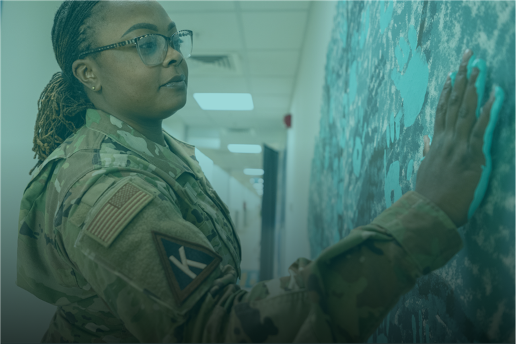 sexual assault prevention and response image where a woman is putting her hand print covered in teal paint on the wall to share awareness around sexual assault