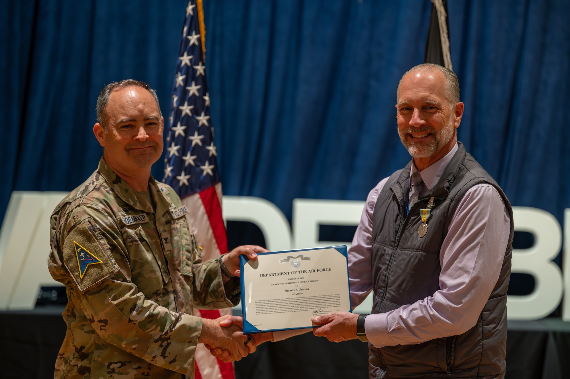 U.S. Space Force Col. Mark Shoemaker, Space Launch Delta 30 commander, left, presents the meritorious civilian service award to Tom Stevens, Space Launch Delta 30 executive director, during a commander’s call at Vandenberg Space Force Base, Calif., June 3, 2025. During the all-call, Shoemaker, along with other SLD 30 leadership, highlighted the achievements of the Guardians and Airmen on the installation over the course of Shoemaker’s command and the execution of the Delta’s strategic objectives.